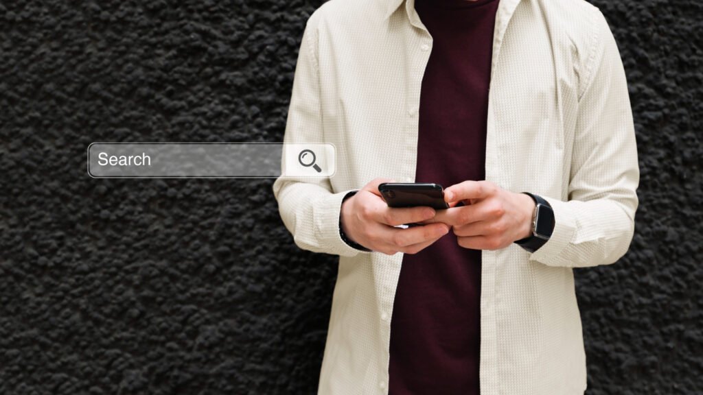 Hombre joven con celular en la mano realizando una búsqueda